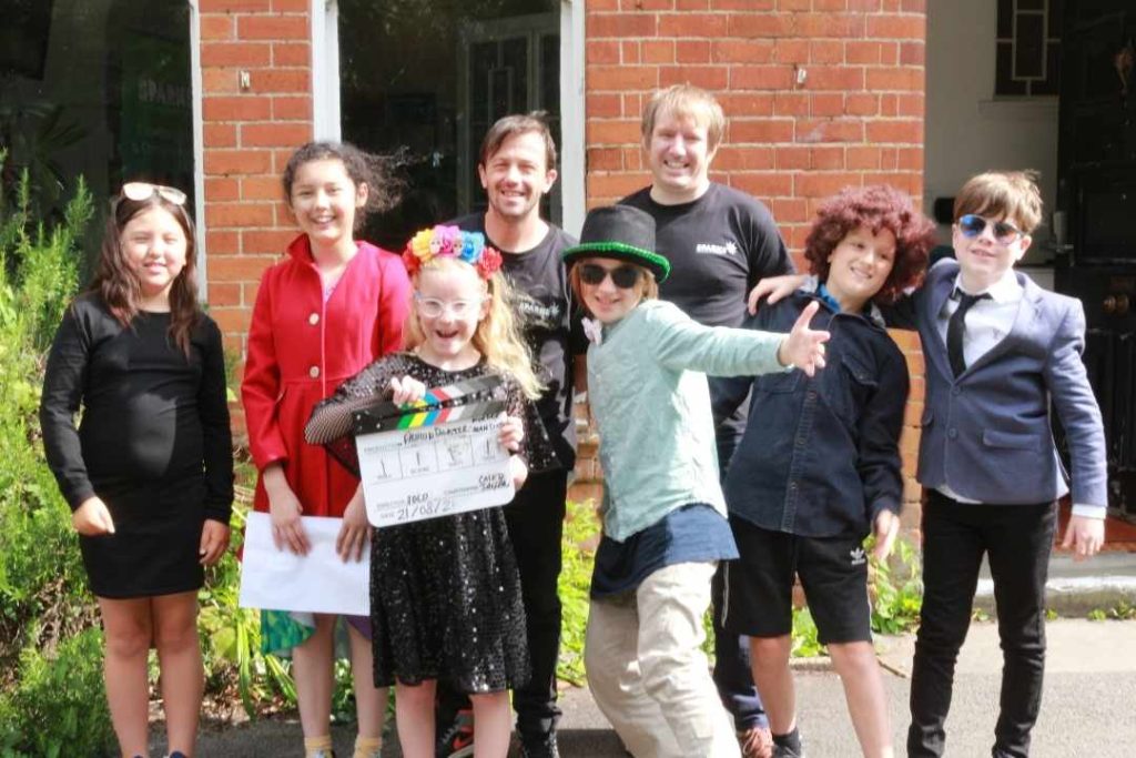 A group of film school students from Sparks Film School Cardiff West pose for a group photo outside on a sunny day. 