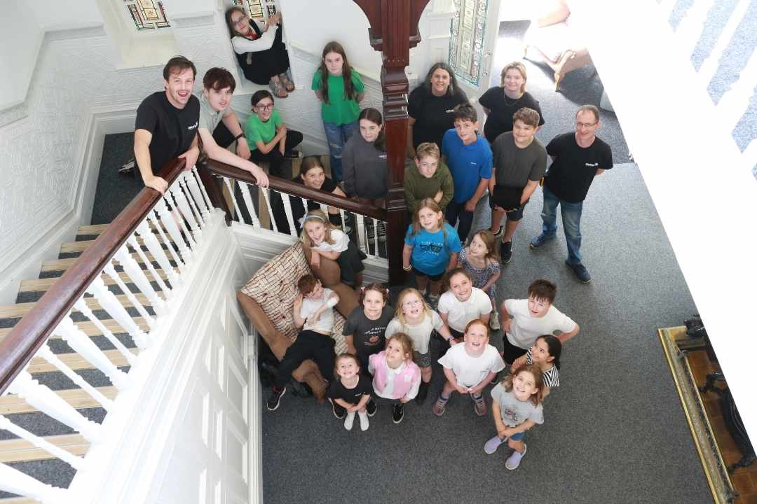 About Us 259 Students of Sparks Film School Cardiff West gather for a group photo at the bottom of a stiar case, the image has been taken from the top of the staircase and they look up at the camera | Meet Alyn and Christine, Heads of Sparks Film School Cardiff West